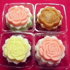 four small cupcakes in plastic containers on a red tablecloth with white and yellow frosting