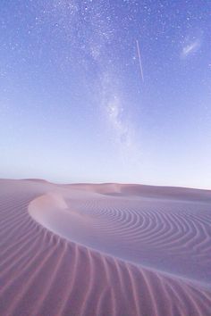 the stars are shining in the sky above sand dunes