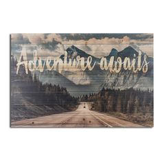 a wooden sign that says adventure awaits on the side of a road with mountains in the background