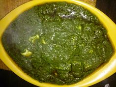 a yellow bowl filled with green sauce on top of a wooden table