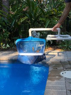 a man is reaching into a swimming pool with an inflatable boat attached to it