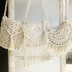 two crocheted purses hanging from hooks on a white door with an old window in the background