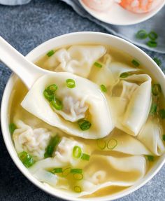 a bowl filled with dumplings and green onions on top of a blue table cloth