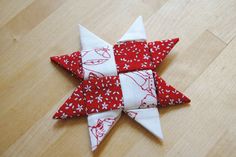 a red and white origami star sitting on top of a wooden floor