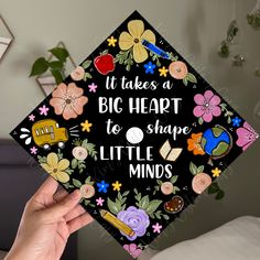 someone holding up a graduation cap that says it takes a big heart to shape little minds