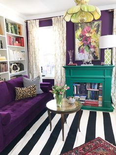 a living room with purple couches and bookshelves on the wall, striped rug