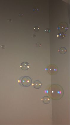 soap bubbles floating in the air on a white wall