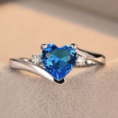 a heart shaped blue topazte ring with three diamonds on the band and an accent diamond in the middle