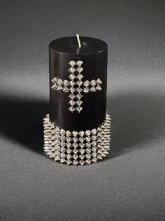 a candle that is sitting on top of a table with chains around it and a cross in the middle