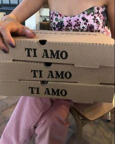 a woman sitting on a chair holding a cardboard box with the words it amo and i amo