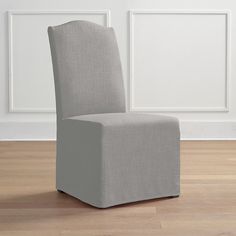 a gray chair sitting on top of a hard wood floor next to a white wall