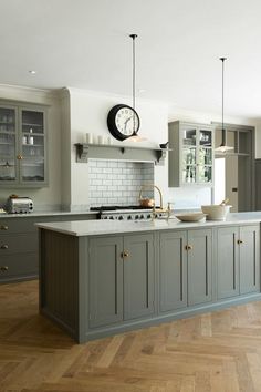 an image of a kitchen setting with wood flooring and grey cabinets on the walls