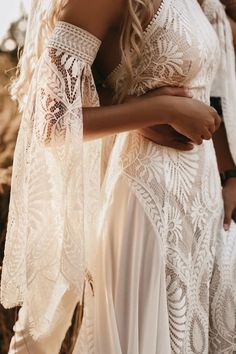 two women in white dresses standing next to each other with their arms around each other