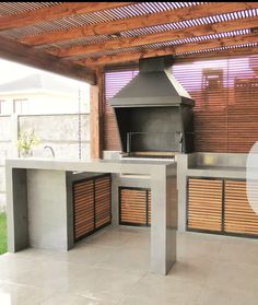 an outdoor kitchen with a grill on the counter and wood slats covering the walls