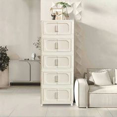 a living room with white furniture and plants on top of the drawers in front of it