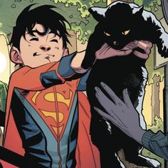 a young man in a superman costume holding a cat