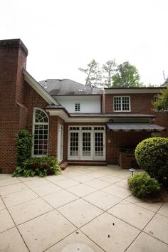 a large brick house with white windows and lots of greenery in the front yard