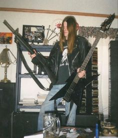 a man with long hair is holding a guitar in his hands and posing for the camera