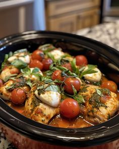 a crock pot filled with tomatoes and mozzarella