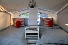 a bed in a tent with two pillows and a lamp on the nightstand next to it