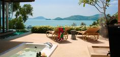 an outdoor jacuzzi with two chairs and a woman sitting in the tub looking out over the water