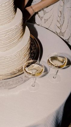 a wedding cake and two glasses of wine on a table