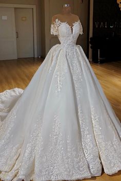 a white wedding dress on display in a room with wooden floors and walls, it is very