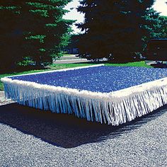 a blue and white table with fringes on it in front of a black truck