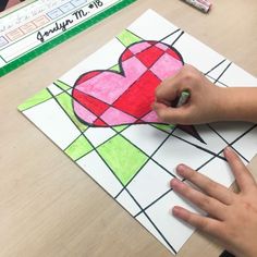 a child's hand holding a piece of paper with a heart drawn on it