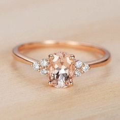 an oval morganite and diamond ring on a wooden surface