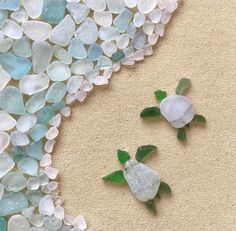 two sea glass turtles sitting on the sand