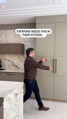 a man walking through a kitchen next to a refrigerator freezer with a thought bubble above it that says everyone needs this in their kitchen