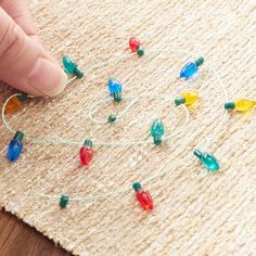 a person is making christmas lights with stringing on the floor and hand pointing at them