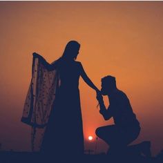 a man kneeling down next to a woman with a veil on her head at sunset