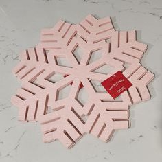 a pink snowflake sitting on top of a table next to a red tag