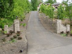 a driveway leading to a house with trees and bushes on either side of the road