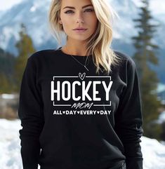 a woman standing in the snow wearing a black hockey sweatshirt that says hockey all day every - day