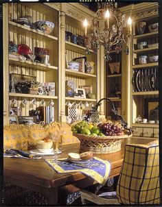 a dining room table and chairs in front of a bookshelf filled with dishes