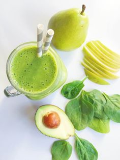 an avocado smoothie with spinach leaves and sliced apples on the side