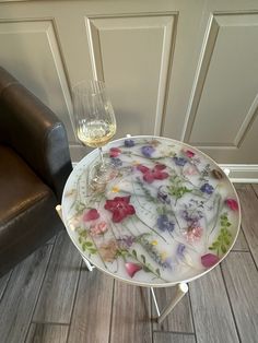 a glass of wine sitting on top of a table next to a brown leather chair