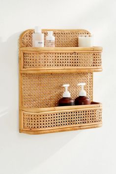 two bamboo shelves with soap and lotion bottles on them, against a white wall