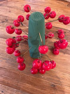 a bunch of red cherries sitting on top of a wooden table next to a green bag