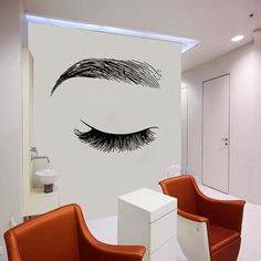 an eye wall decal in a modern bathroom with orange chairs and a white sink