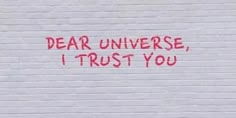 graffiti written on the side of a building reads dear universe, i trust you with red spray paint