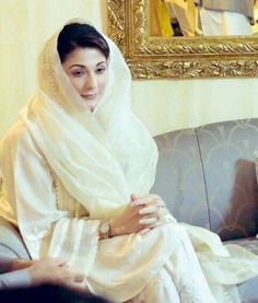 a woman sitting on top of a couch wearing a white shawl