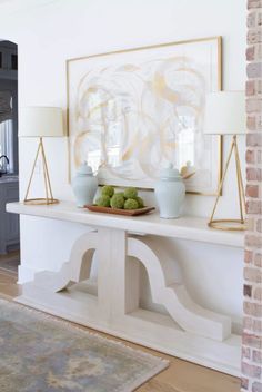 a white table with two vases on it and a painting in the back ground