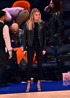 a woman standing on top of a basketball court next to a man in a black jacket