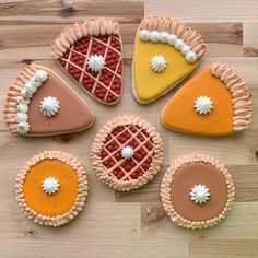 six decorated pies on a wooden table