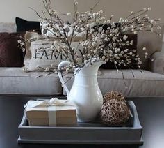 a white pitcher sitting on top of a tray next to a box with a wrapped present