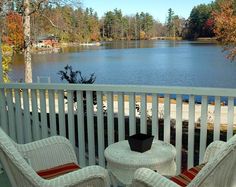 two chairs and a table on a porch overlooking a lake